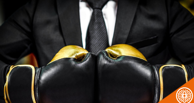 Featured-Image_Chest-of-Man-in-suit-and-tie-with-hands-together-with-gold-and-black-boxing-gloves