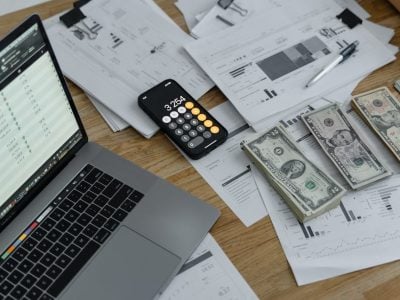 Banknotes, calculator, and laptop on a table.