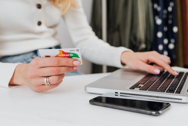 A woman holding a credit card while using her laptop